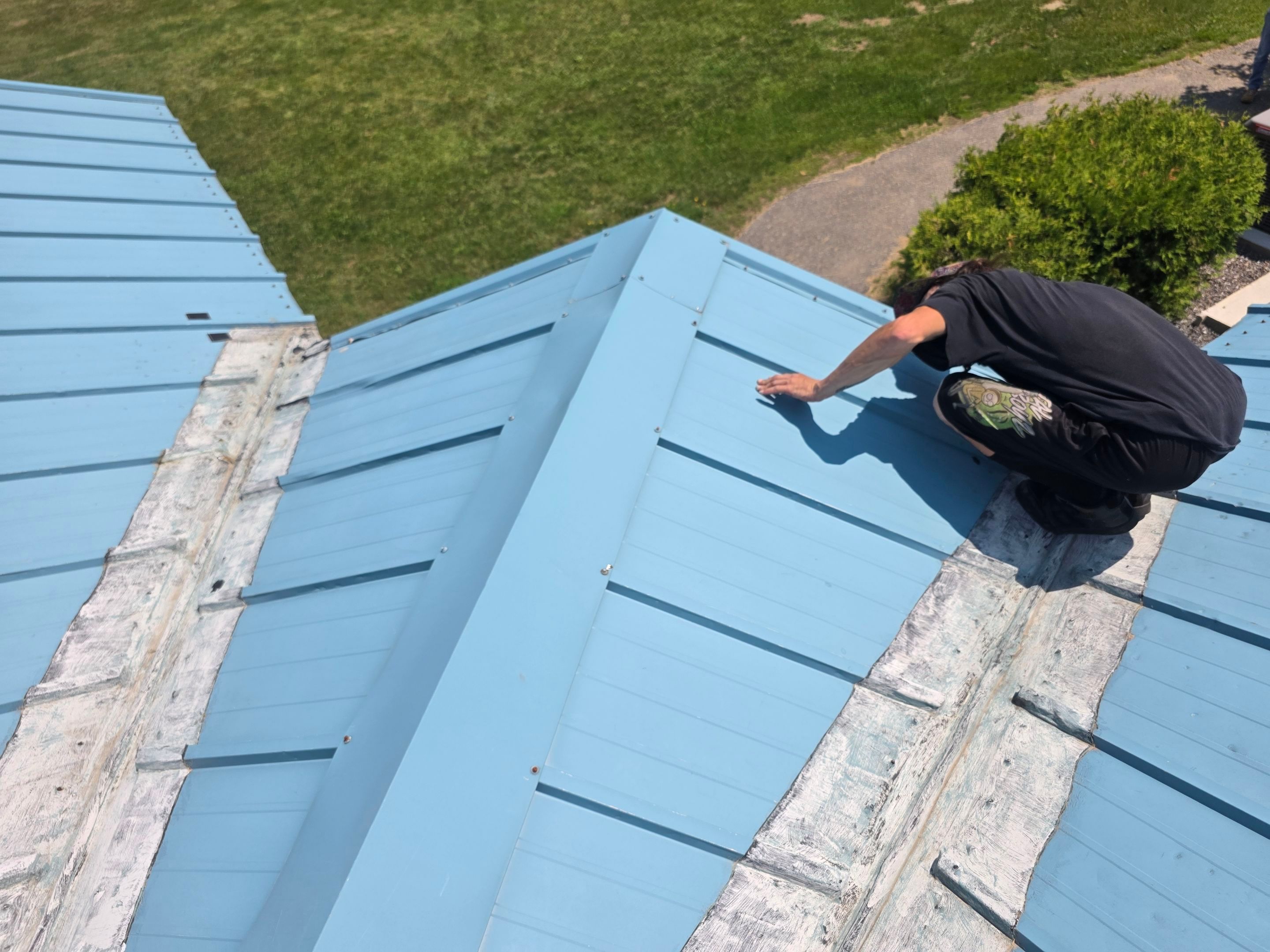 Light blue corrugated metal roof with a worker finishing a ridge
