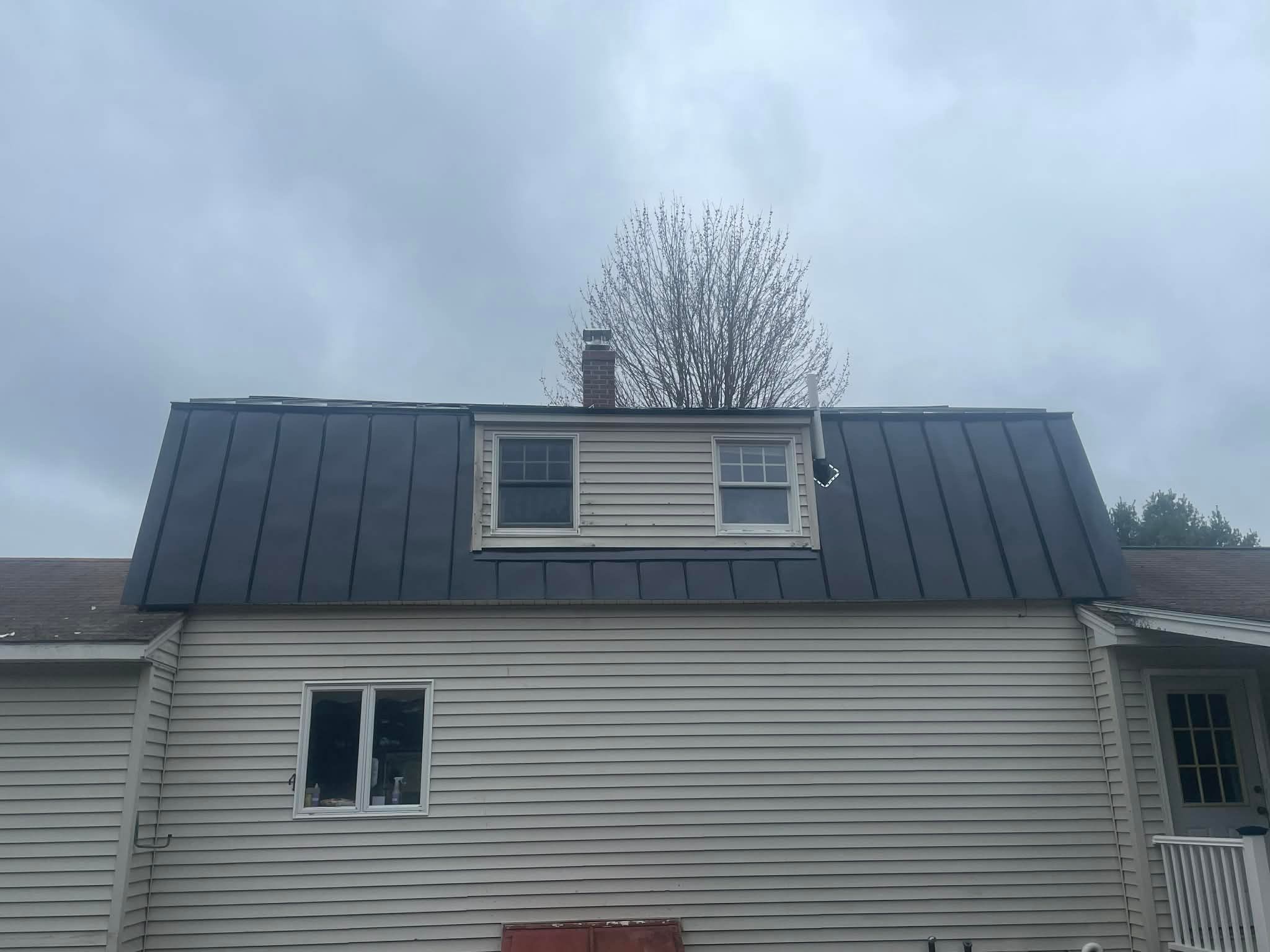 Finished dark standing-seam roof around a dormer