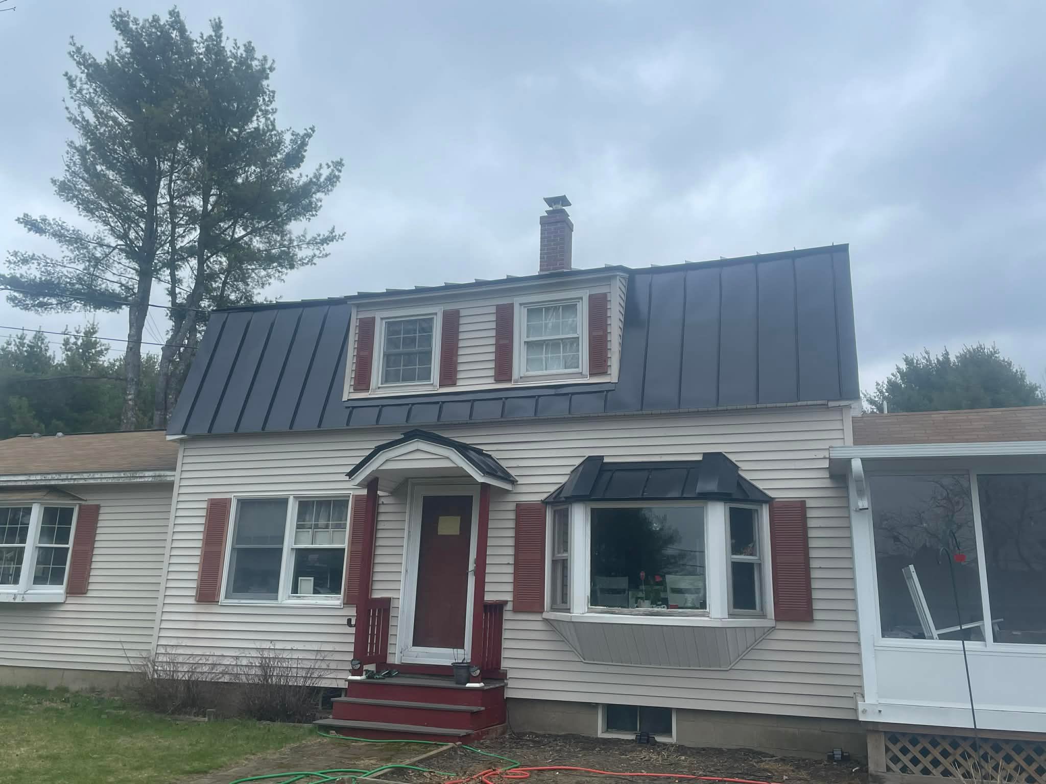 Completed dark standing-seam roof on a home with dormers