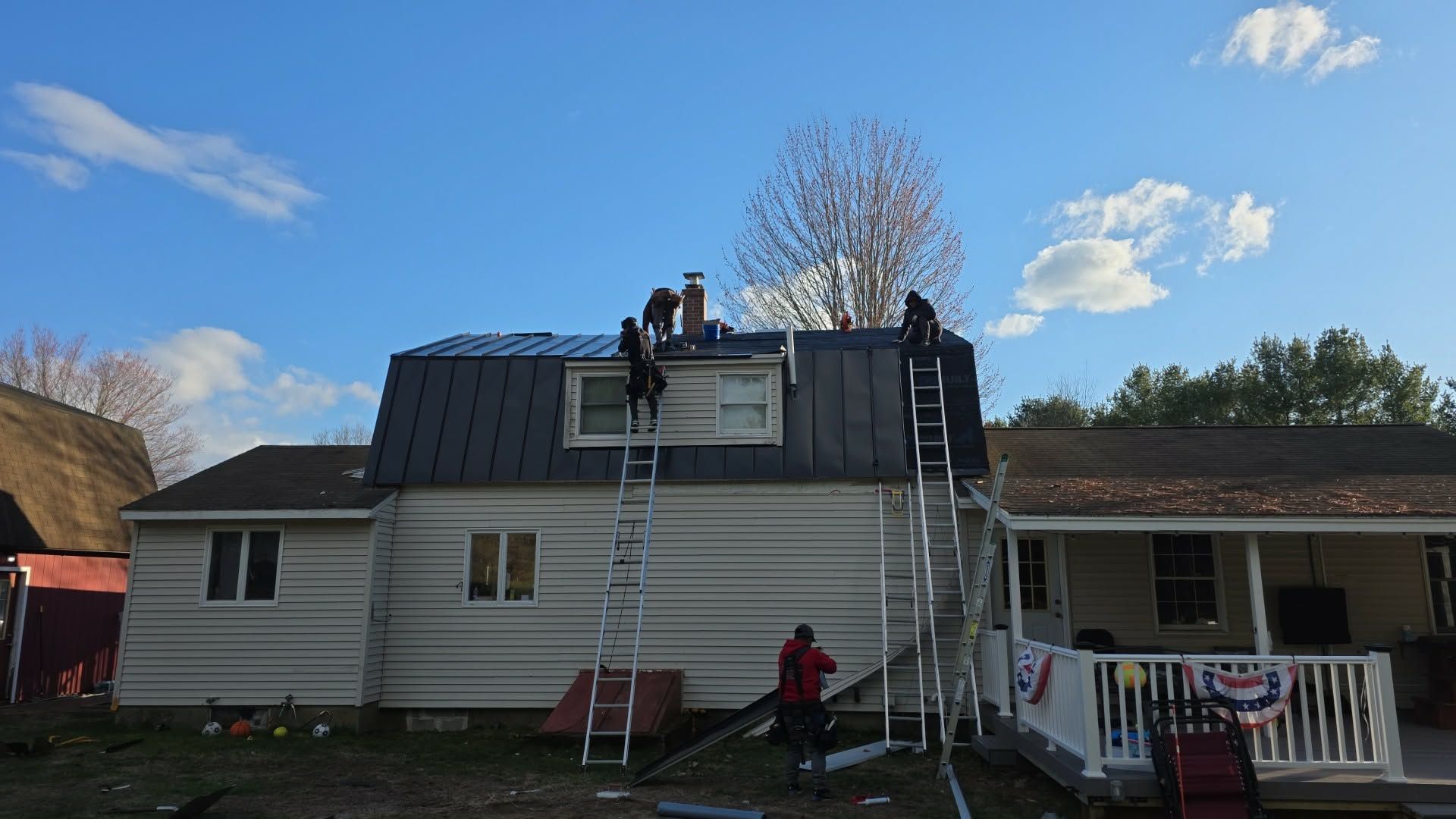 Crew installing a dark metal roof on a home